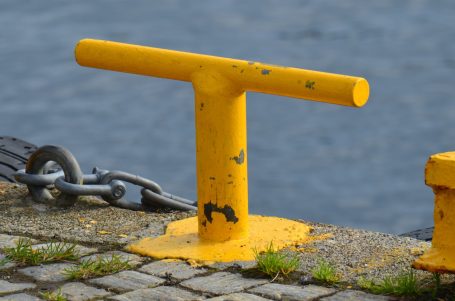 Gelbe Mooring-Anlage an einem Steg, daneben eine Kette und fließendes Wasser.