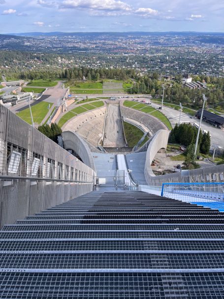 Blick von einer Skisprungschanze auf die Landebahn und die umliegende Landschaft.