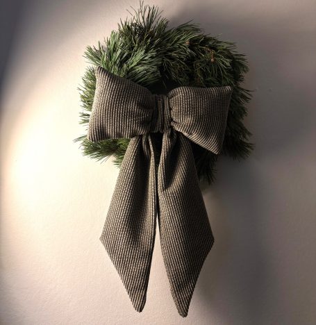 Ein runder Kranz aus Tannenzweigen mit einer großen, grauen Schleife.
