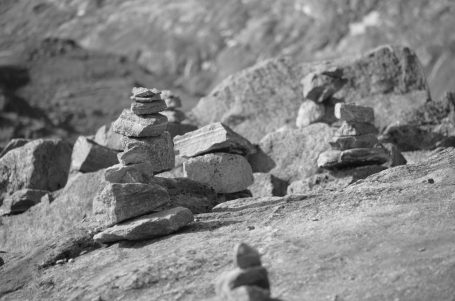 Kleine Steinhaufen auf einer kargen Landschaft, in Schwarz-Weiß fotografiert.
