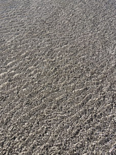 Eine sandige Oberfläche mit sanften Wellen und Schattierungen.