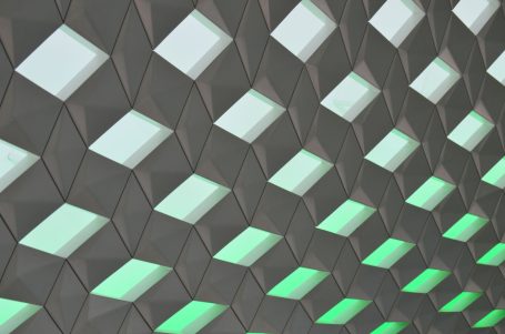Abstrakte Wandstruktur mit grünlich leuchtenden, quadratischen Flächen.
