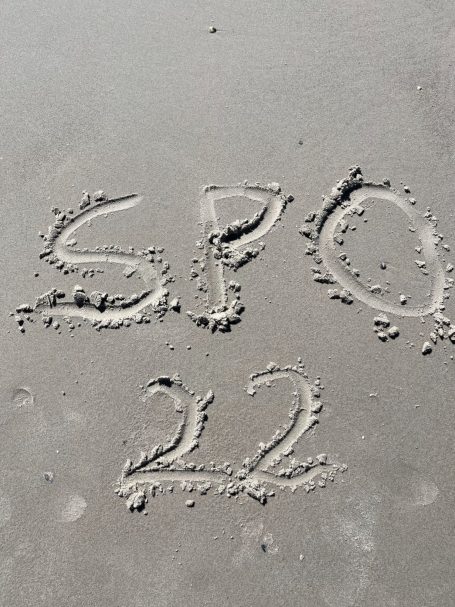 Die Buchstaben "SPO" und die Zahl "22" sind in den Sand geschrieben.