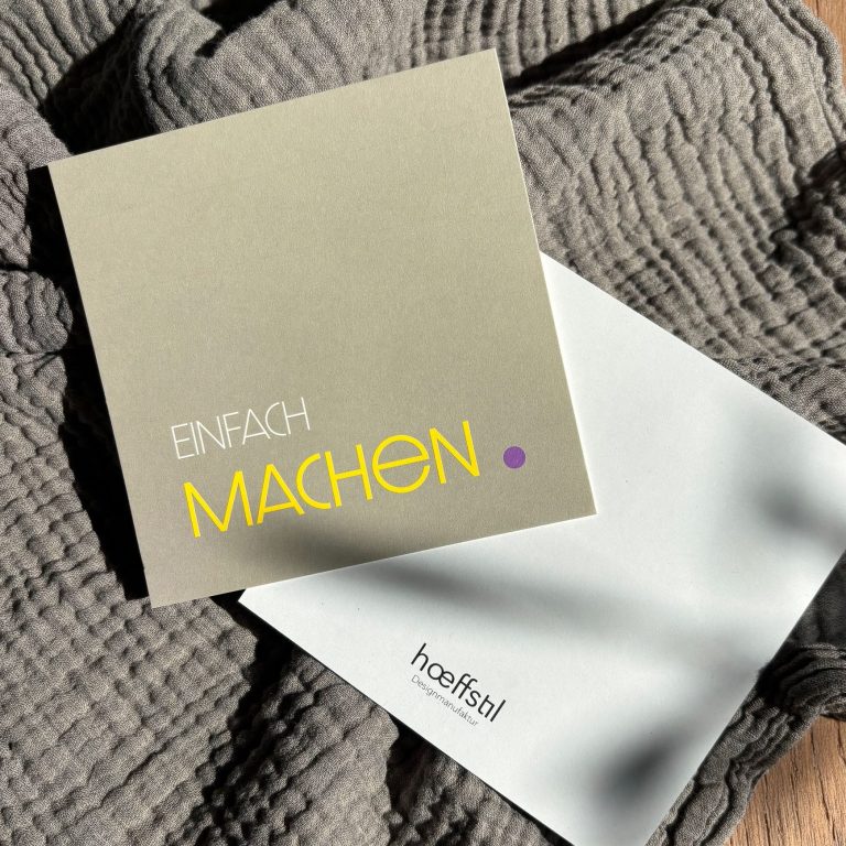 Karte - Vorderseite mit Schriftzug "Einfach machen" und weißer Rückseite mit Logo auf einem grauen Tuch.