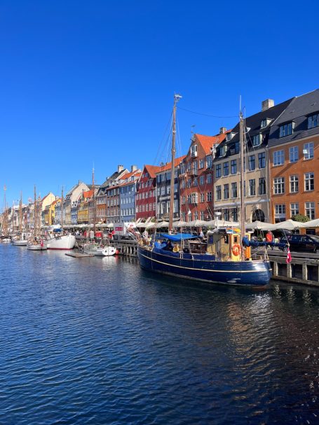 Bunte Häuser am Wasser mit Booten, klarer blauer Himmel darüber.