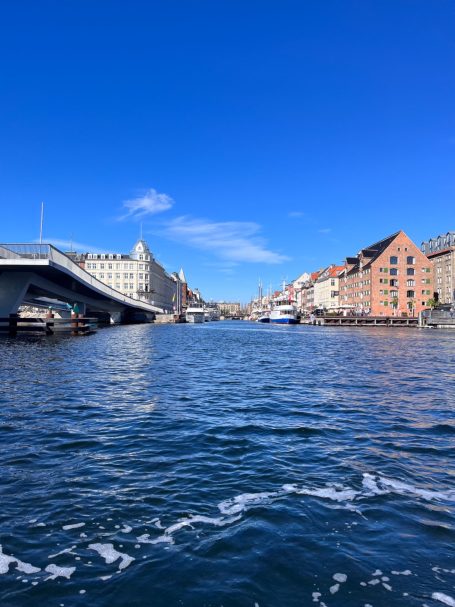 Blick auf einen Kanal mit farbenfrohen Gebäuden und klarem blauen Himmel.