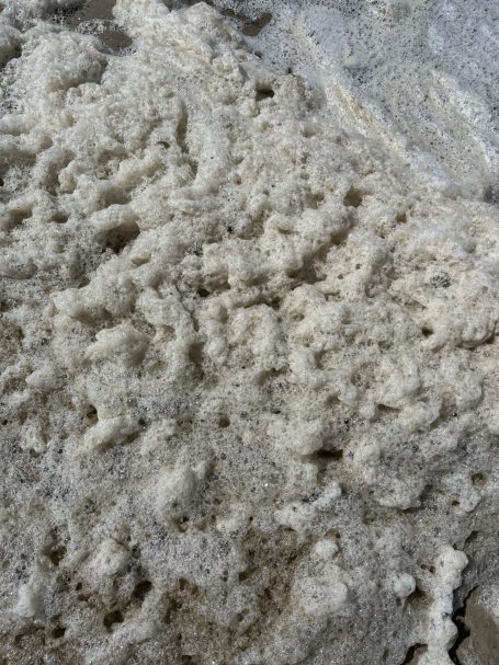 Helle, schaumige Masse mit unregelmäßiger Textur und kleinen Blasen.