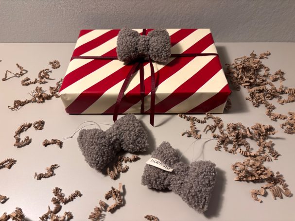 Geschenk mit rot-weißer Streifenverpackung und grauen Schleifen dekoriert.