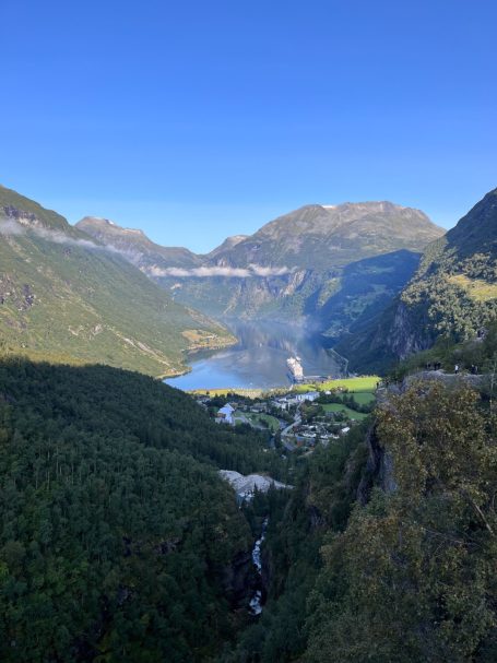 Berglandschaft mit einem klaren See, umgeben von grünen Tälern und hohen, majestätischen Bergen.